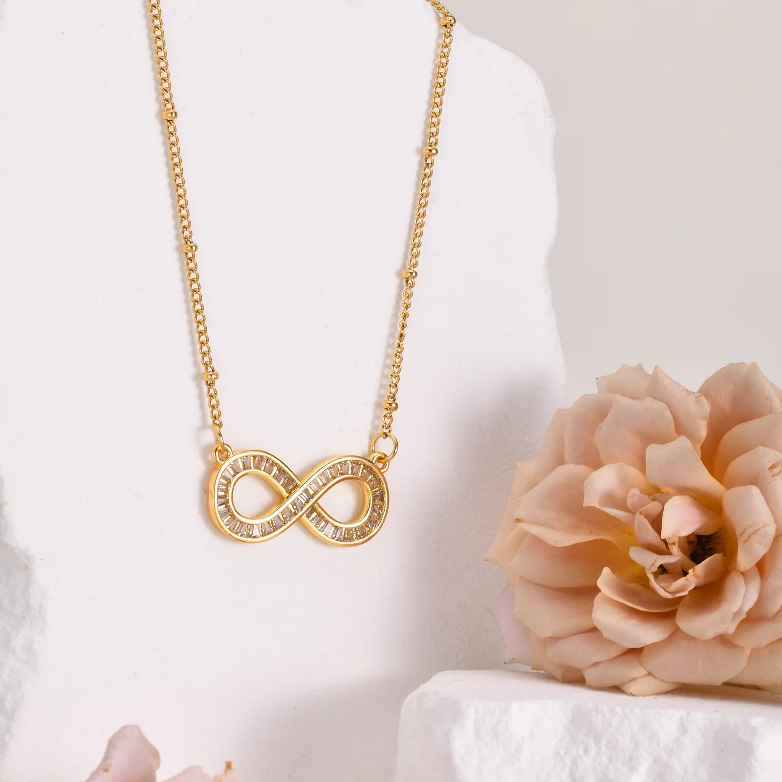 Collar con colgante de infinito de acero inoxidable chapado en oro de 14 quilates con cadena de cuentas y circonitas .